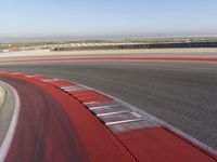 an empty track at a motorsports club with some red and white stripeing on it