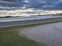 a red race car on a track in a parking lot with cloudy skies above it