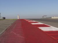 an empty track at a motorsports club with some red and white stripeing on it