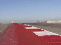 an empty track at a motorsports club with some red and white stripeing on it