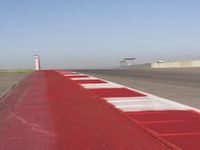 an empty track at a motorsports club with some red and white stripeing on it