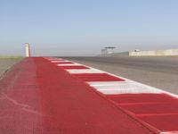 an empty track at a motorsports club with some red and white stripeing on it