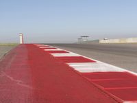 an empty track at a motorsports club with some red and white stripeing on it