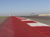 an empty track at a motorsports club with some red and white stripeing on it