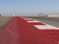 an empty track at a motorsports club with some red and white stripeing on it