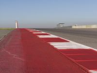 an empty track at a motorsports club with some red and white stripeing on it