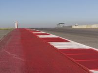 an empty track at a motorsports club with some red and white stripeing on it