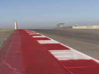 an empty track at a motorsports club with some red and white stripeing on it