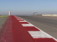 an empty track at a motorsports club with some red and white stripeing on it