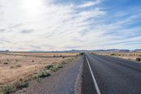 a single motorcycle rider and his shadow on a wide open road in the distance is the desert