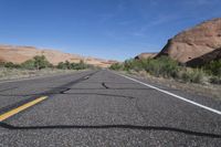 a desert with a road and a mountain in the background and a bike that is leaning against a car