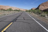 a desert with a road and a mountain in the background and a bike that is leaning against a car