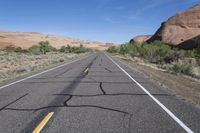 a desert with a road and a mountain in the background and a bike that is leaning against a car