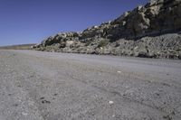 a dirt road with rocks on the side and a motorcycle parked at the end in the center of it