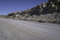 a dirt road with rocks on the side and a motorcycle parked at the end in the center of it