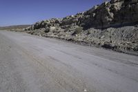 a dirt road with rocks on the side and a motorcycle parked at the end in the center of it