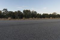 a long empty road with mountains in the distance with a car in the foreground