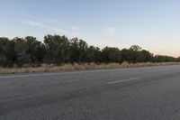 a long empty road with mountains in the distance with a car in the foreground