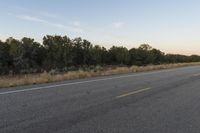 a long empty road with mountains in the distance with a car in the foreground