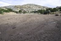 an empty field is shown with a mountain in the background and some dirt on it