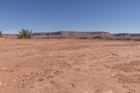 a very dry, arid ground in the desert with rocks and trees nearby for background