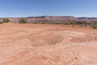 a very dry, arid ground in the desert with rocks and trees nearby for background