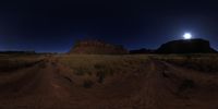 a landscape with dirt roads and the moon setting behind it and a tall hill in the distance