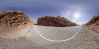 a wide angle photo of a road going up the hill to the camera with a camera lens