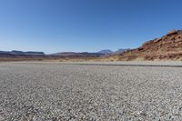 an empty street in the middle of a desert with mountains and sky behind it and in the foreground, a single motorcycle stands with the vehicle