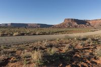 a mountain road runs along an expanse of dry grass in an arid area in the distance