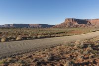 a mountain road runs along an expanse of dry grass in an arid area in the distance