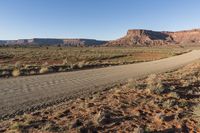 a mountain road runs along an expanse of dry grass in an arid area in the distance