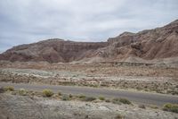 desert and rock with road near it, on cloudy day, with blue sky and wispy clouds