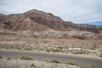 desert and rock with road near it, on cloudy day, with blue sky and wispy clouds