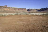 a dry area with dirt, some grass and some rocks in the foreground and the mountains