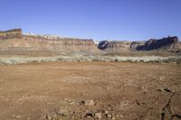 a dry area with dirt, some grass and some rocks in the foreground and the mountains