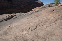 a person on a mountain holding a white frisbee walking up a cliff side