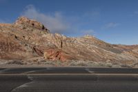 a red rocks formation in the middle of the road in front of a mountain range