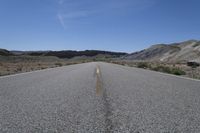 there is a empty empty road between two mountains in the distance, with a car on the side