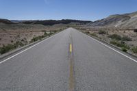 there is a empty empty road between two mountains in the distance, with a car on the side