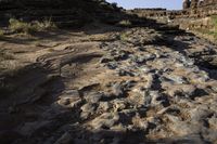 the ground is covered in rocks near a rocky stream on top of the desert terrain