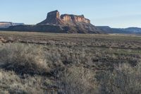 an image of a dirt road that runs through the desert with a rock formation in the background