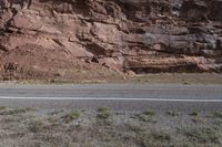 a person riding a motorcycle along a narrow road through rocks and sand cliffs a grassy area on both sides