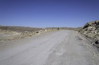 a gravel road leads to an open field of tall rocks, in a mountainous setting