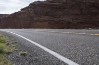 a person riding a motorcycle along a narrow road through rocks and sand cliffs a grassy area on both sides