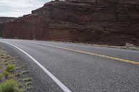 a person riding a motorcycle along a narrow road through rocks and sand cliffs a grassy area on both sides