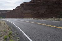 a person riding a motorcycle along a narrow road through rocks and sand cliffs a grassy area on both sides