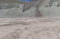 some sand mountains and hills and the sky with clouds above it, and there are no leaves on the ground