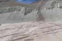 some sand mountains and hills and the sky with clouds above it, and there are no leaves on the ground