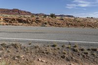 a long road stretches through a desert area with mountains in the background and a desert landscape in the foreground